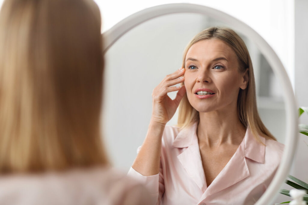 Closeup Shot Of Middle Aged Beautiful Woman Looking In Mirror At Home