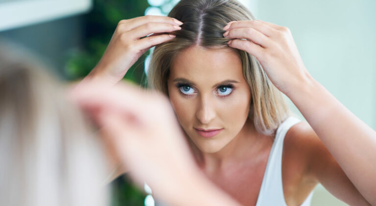 Happy woman brushing hair in bathroom having problem with hair loss