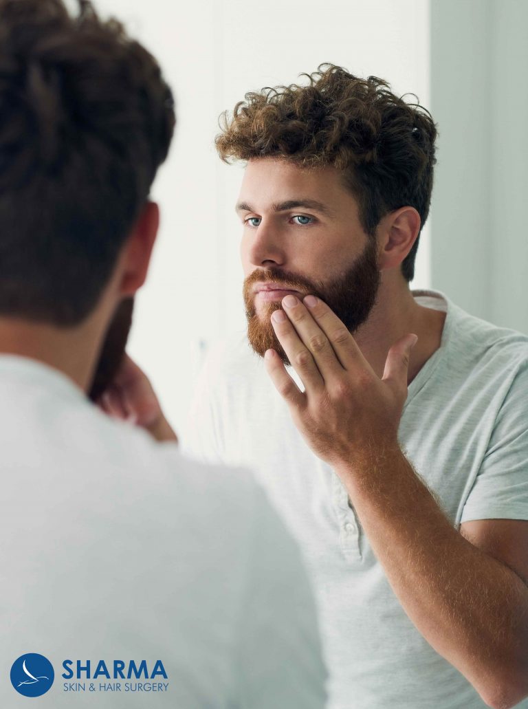 person assessing their beard in a mirror